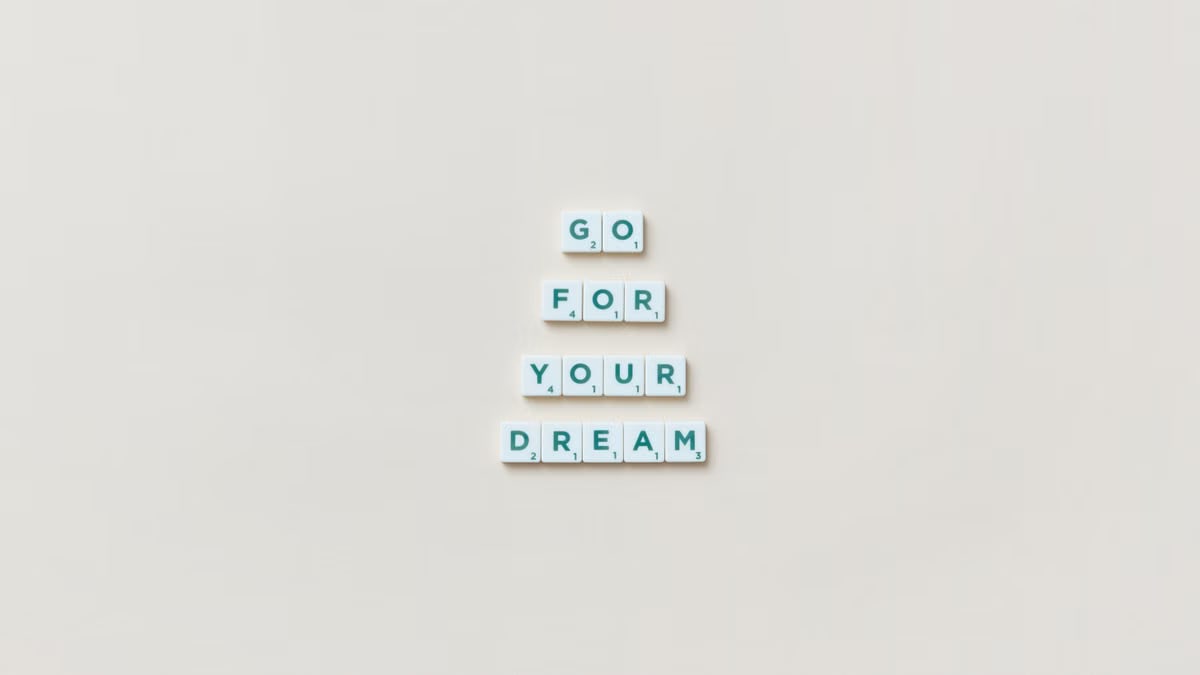 Inspirational text 'Go For Your Dream' made from Scrabble tiles on a plain background.